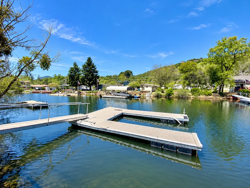 A serene lake with a dock extending into the water, surrounded by trees and mountains.