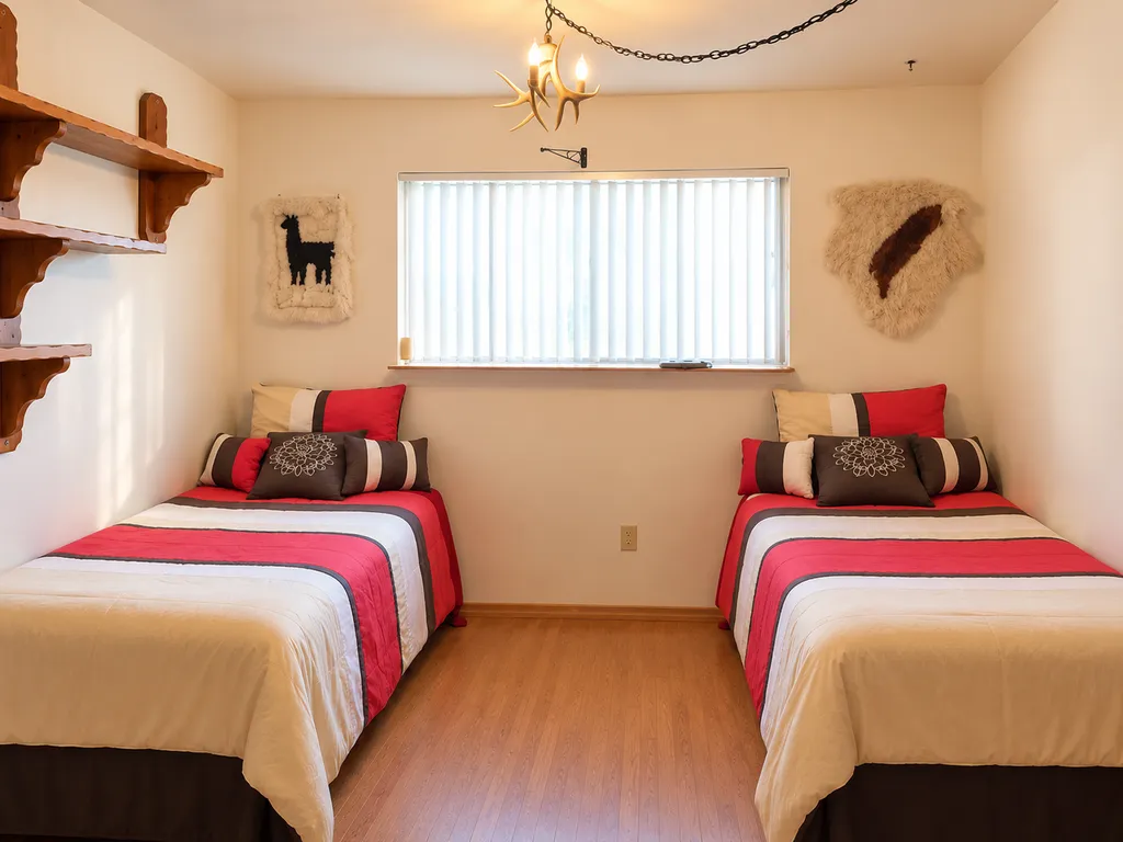 Two twin beds with red and white bedding in a small bedroom with a window.
